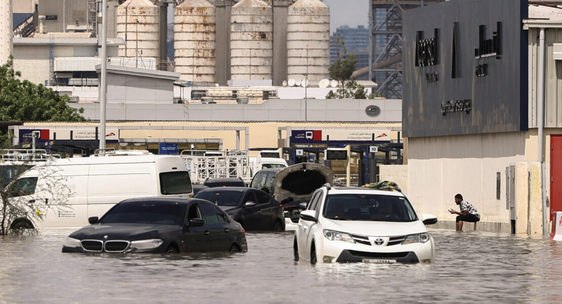 A person sits near vehicles stranded in flood water caused by heavy rains in Dubai, United Arab Emirates, April 17, 2024. REUTERS/Amr Alfiky