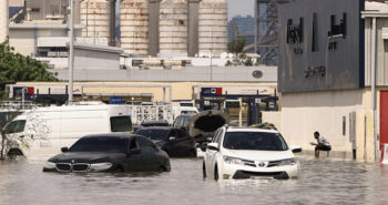 A person sits near vehicles stranded in flood water caused by heavy rains in Dubai, United Arab Emirates, April 17, 2024. REUTERS/Amr Alfiky